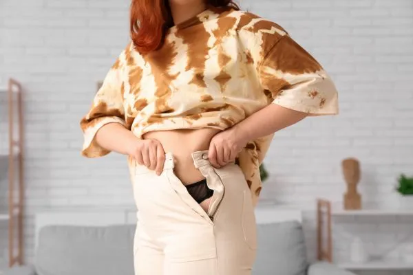 Image of woman trying to do her trousers up after pregnancy weight gain Yeovil