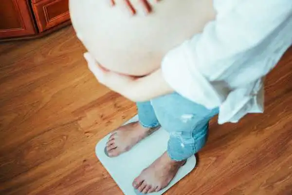 Image of woman weighing herself and experiencing weight gain through pregnancy Yeovil